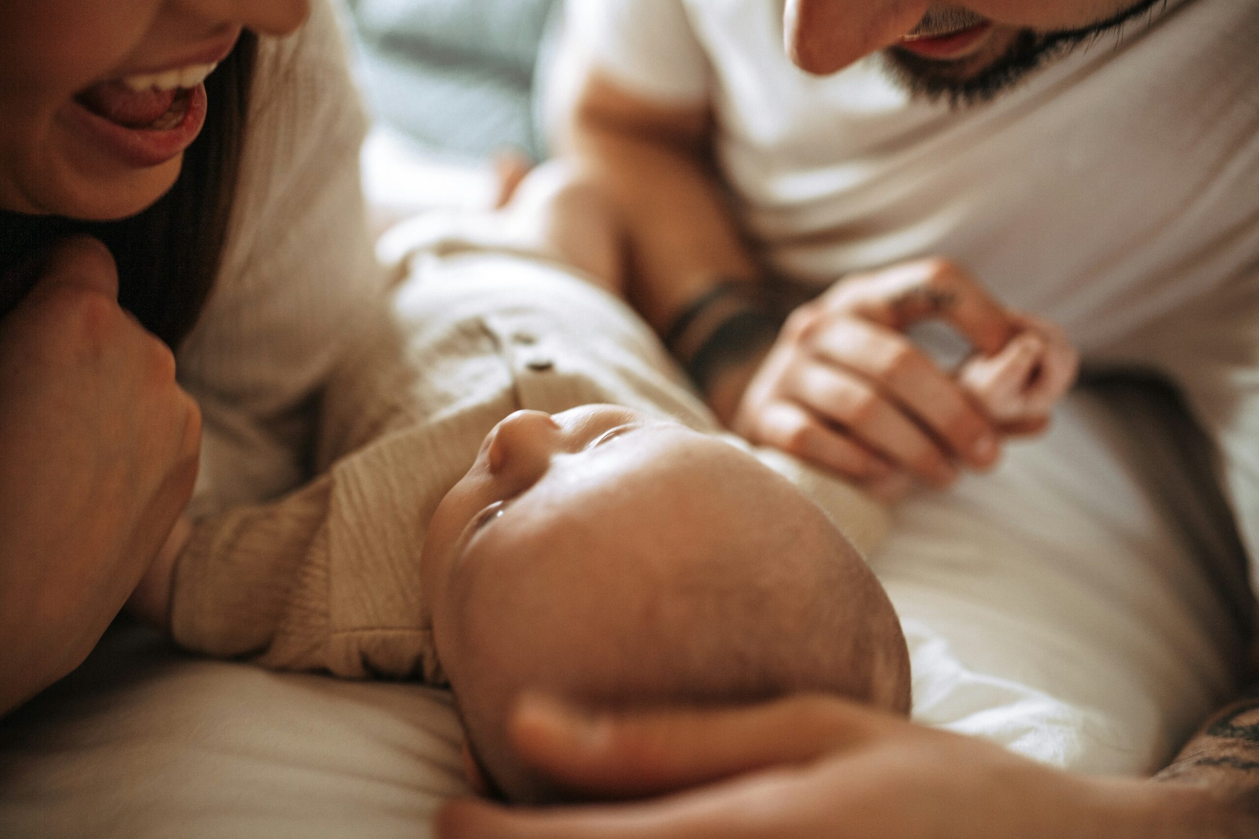 2 parents laying down next to their baby.