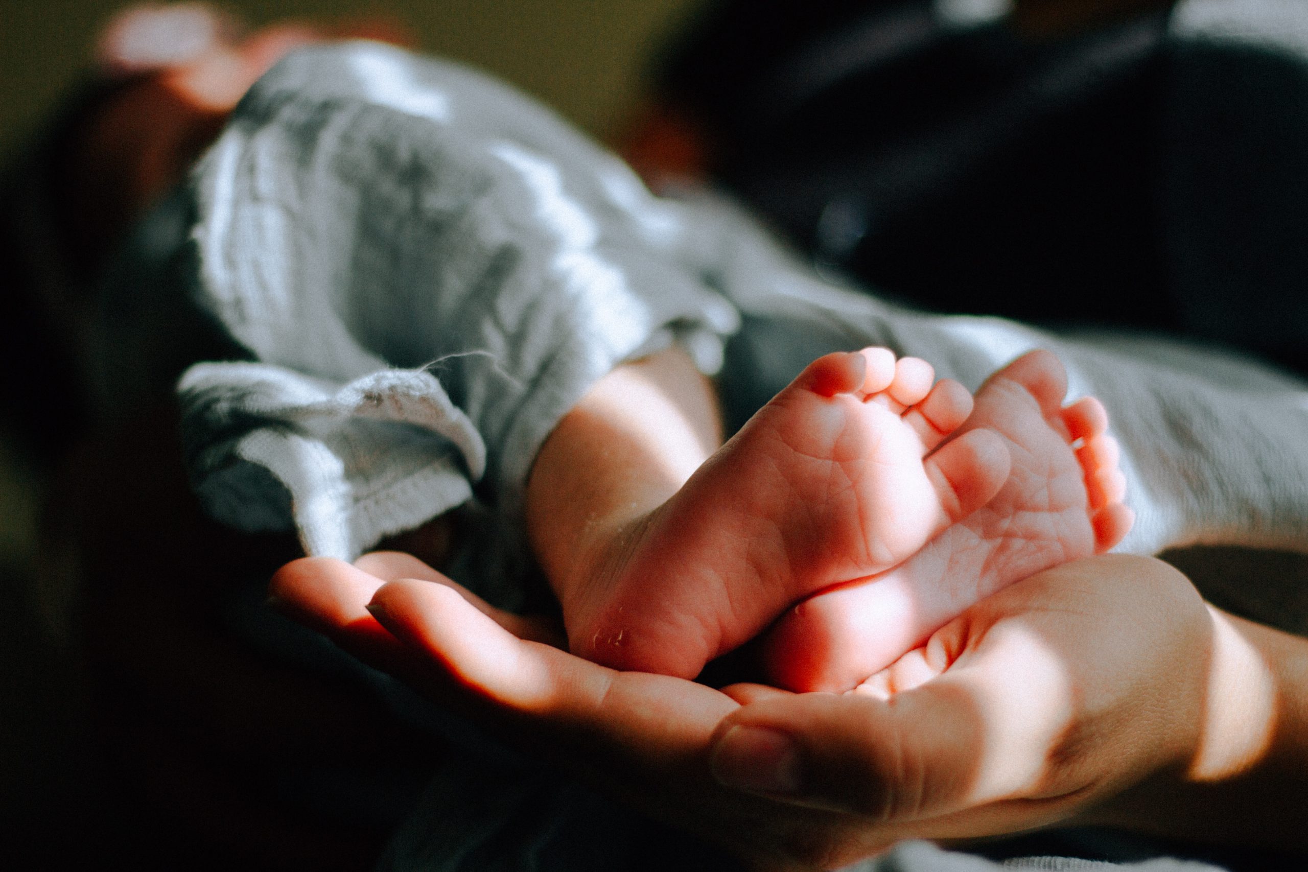 baby's feet being held by postpartum doula's hand.