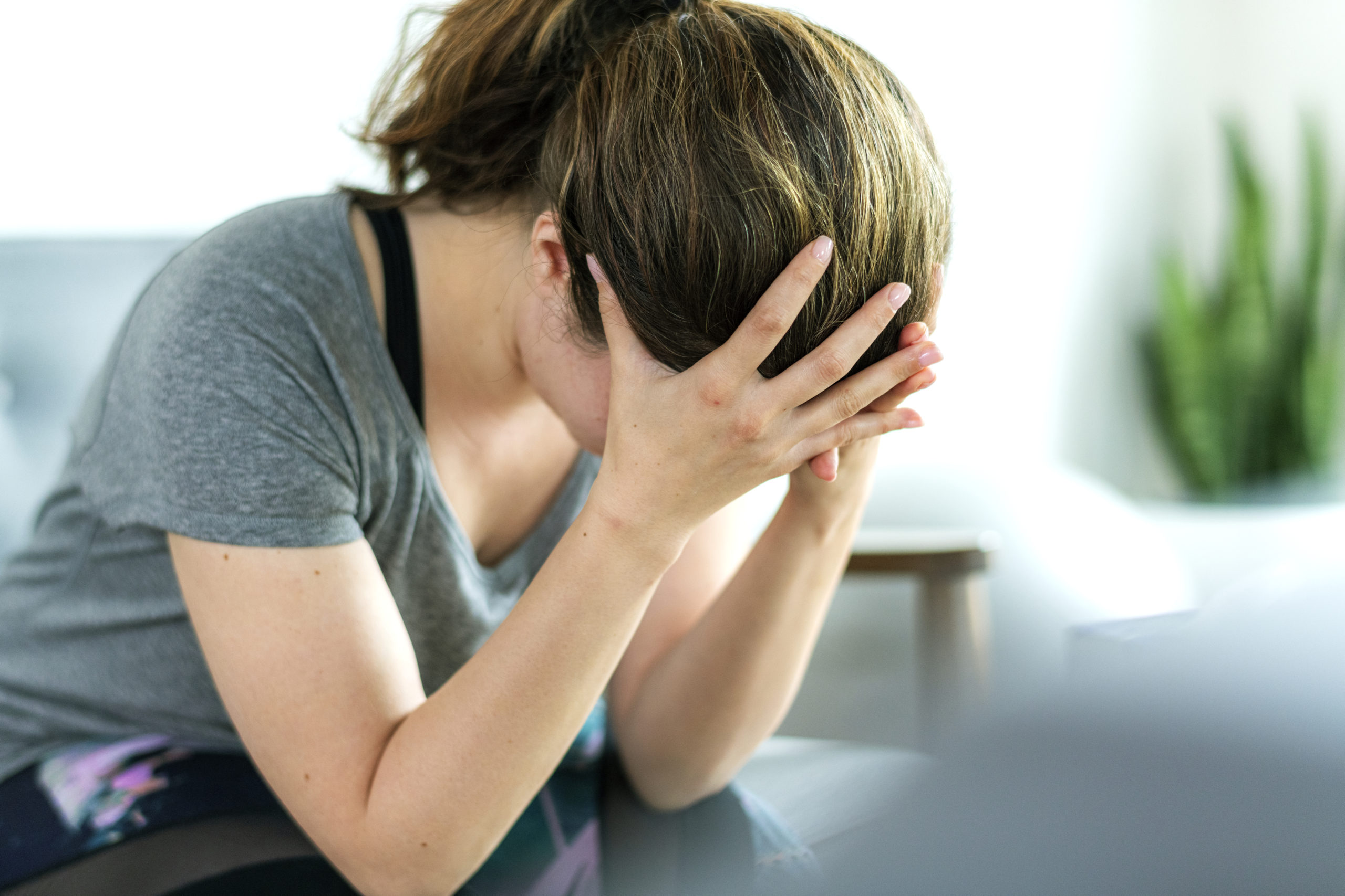 person holding head in their hands while experiencing PMADs