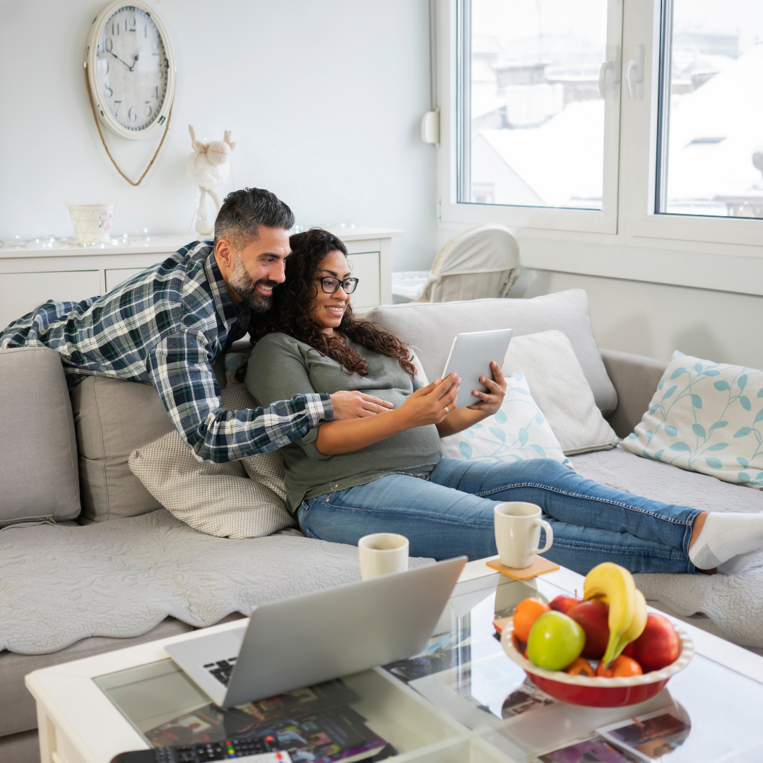 2 parents reading a book on a tablet while pregnant
