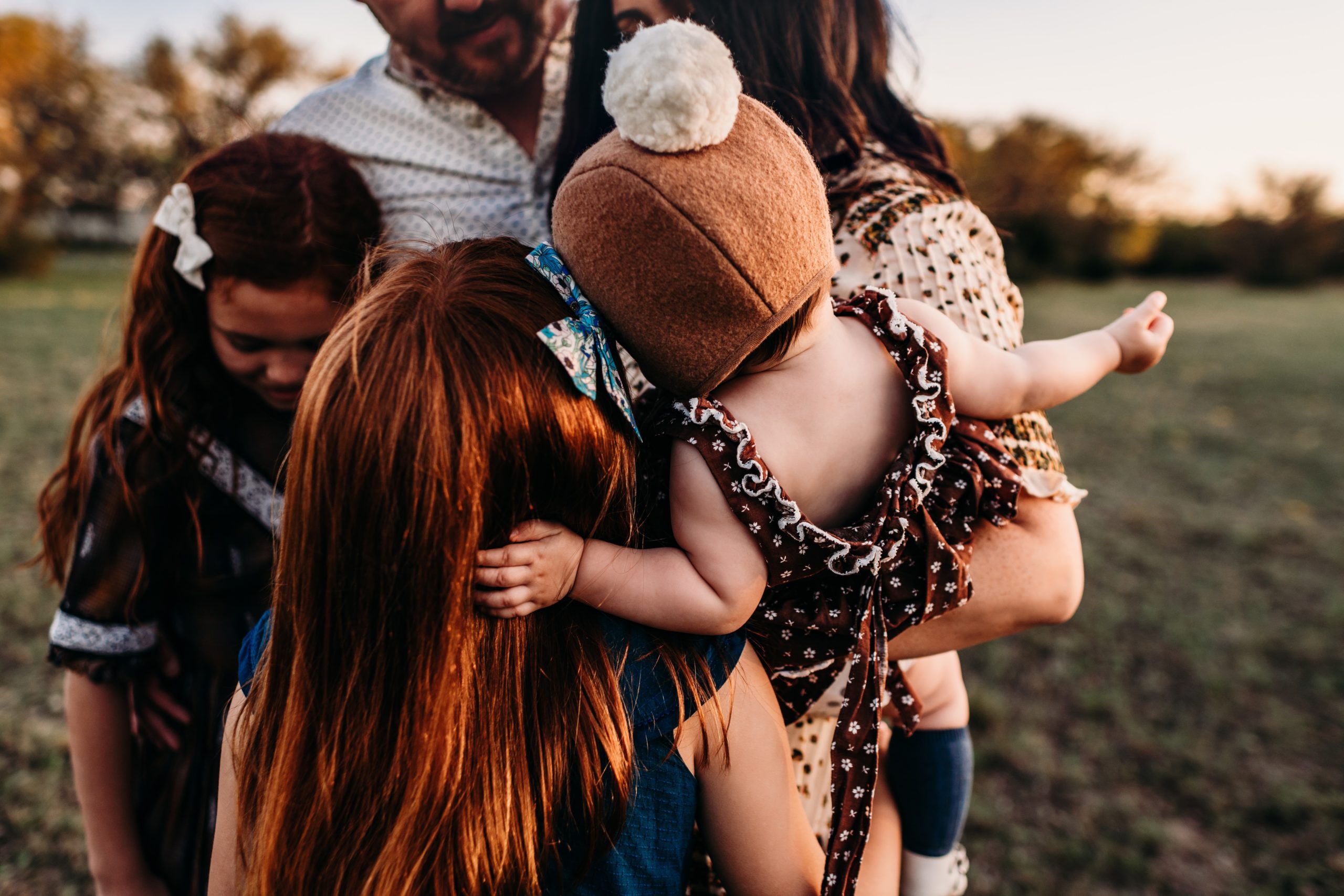 a family of 5 hugging at sunset.