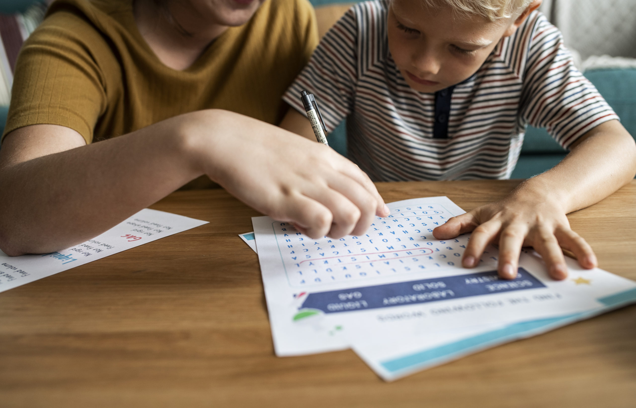 nanny working with kid on homework at a table