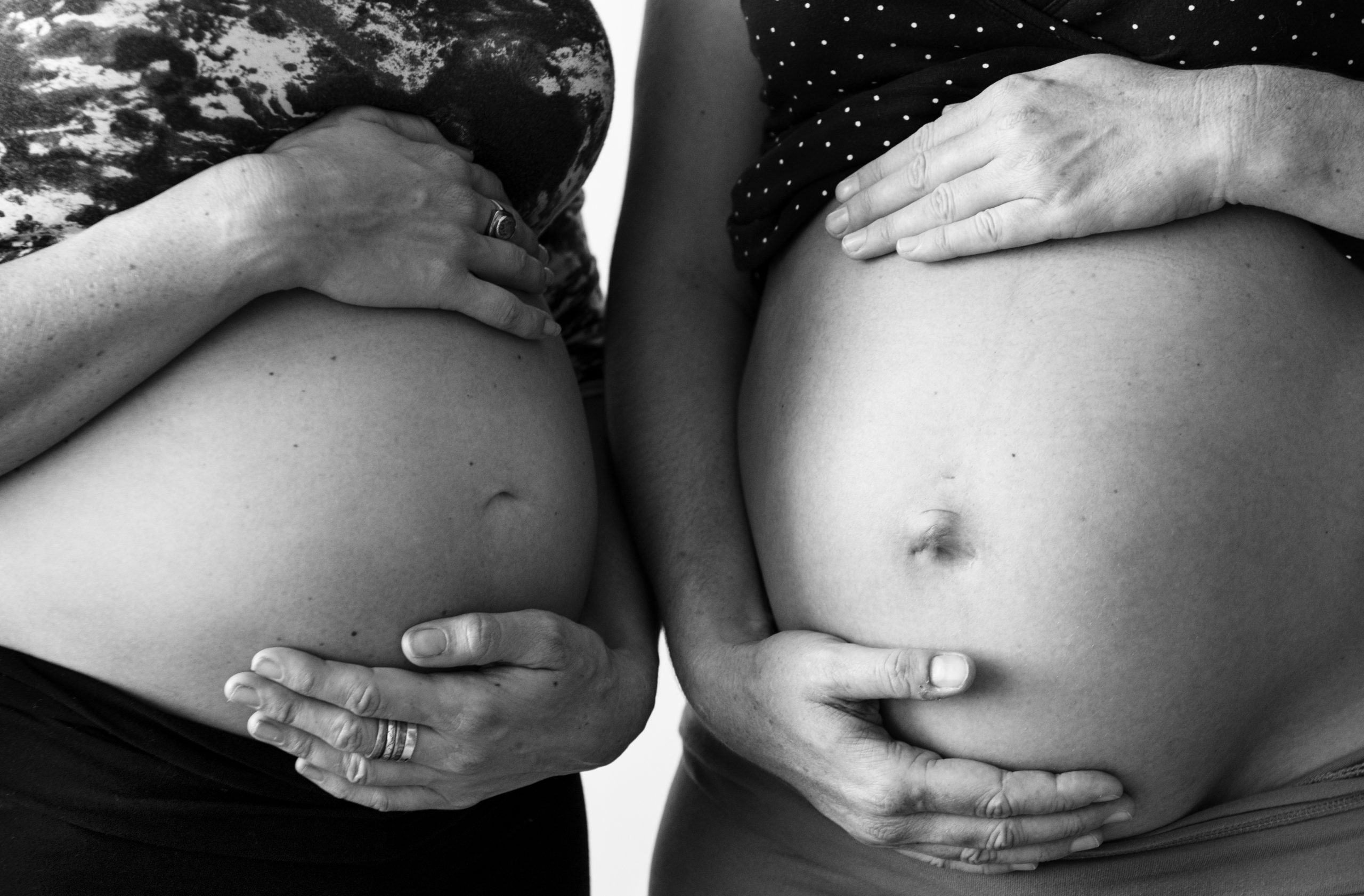 two pregnant people holding their stomachs during class.