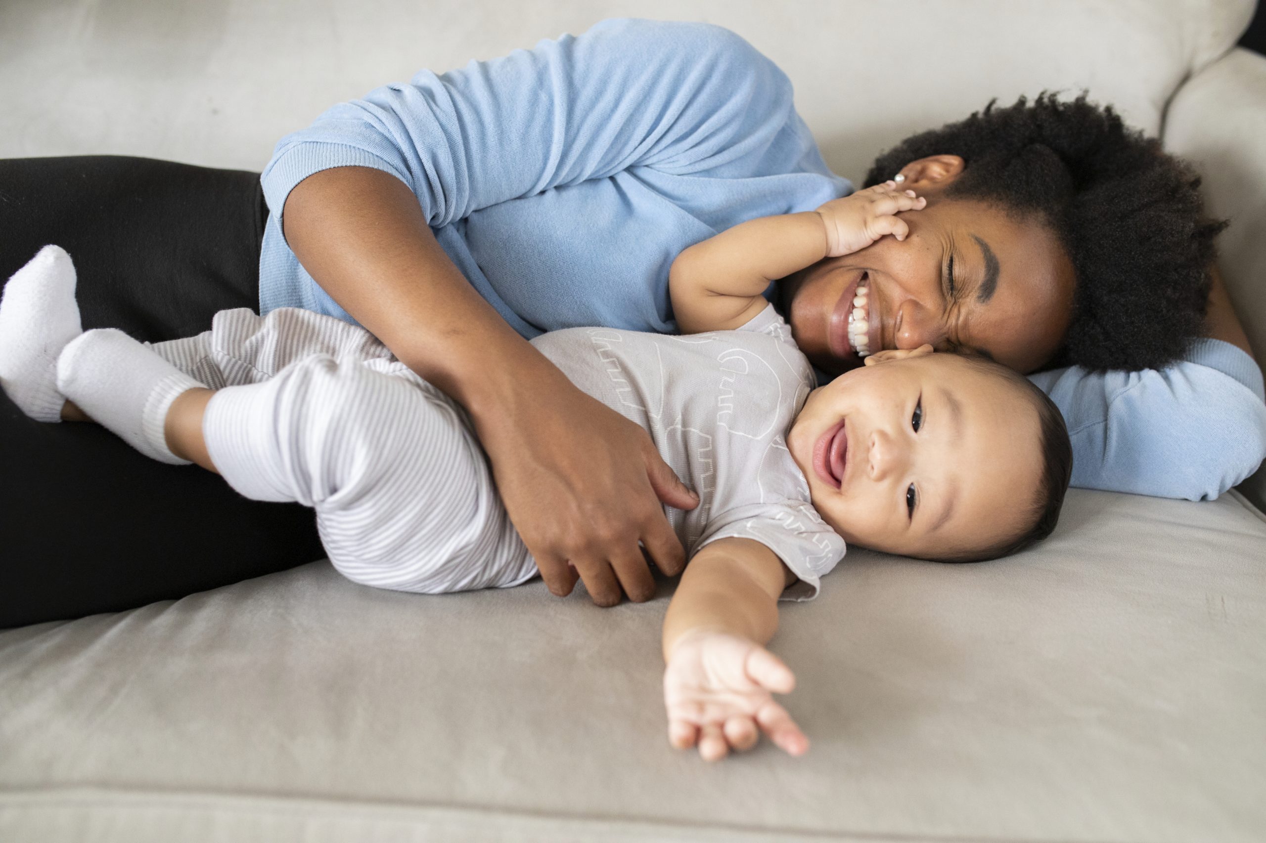 smiling parent and baby snuggling on couch.