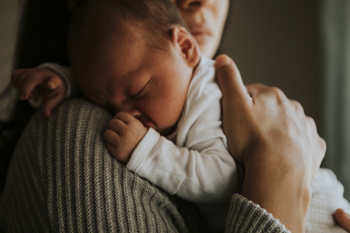 doula holding sleeping baby on their shoulder.
