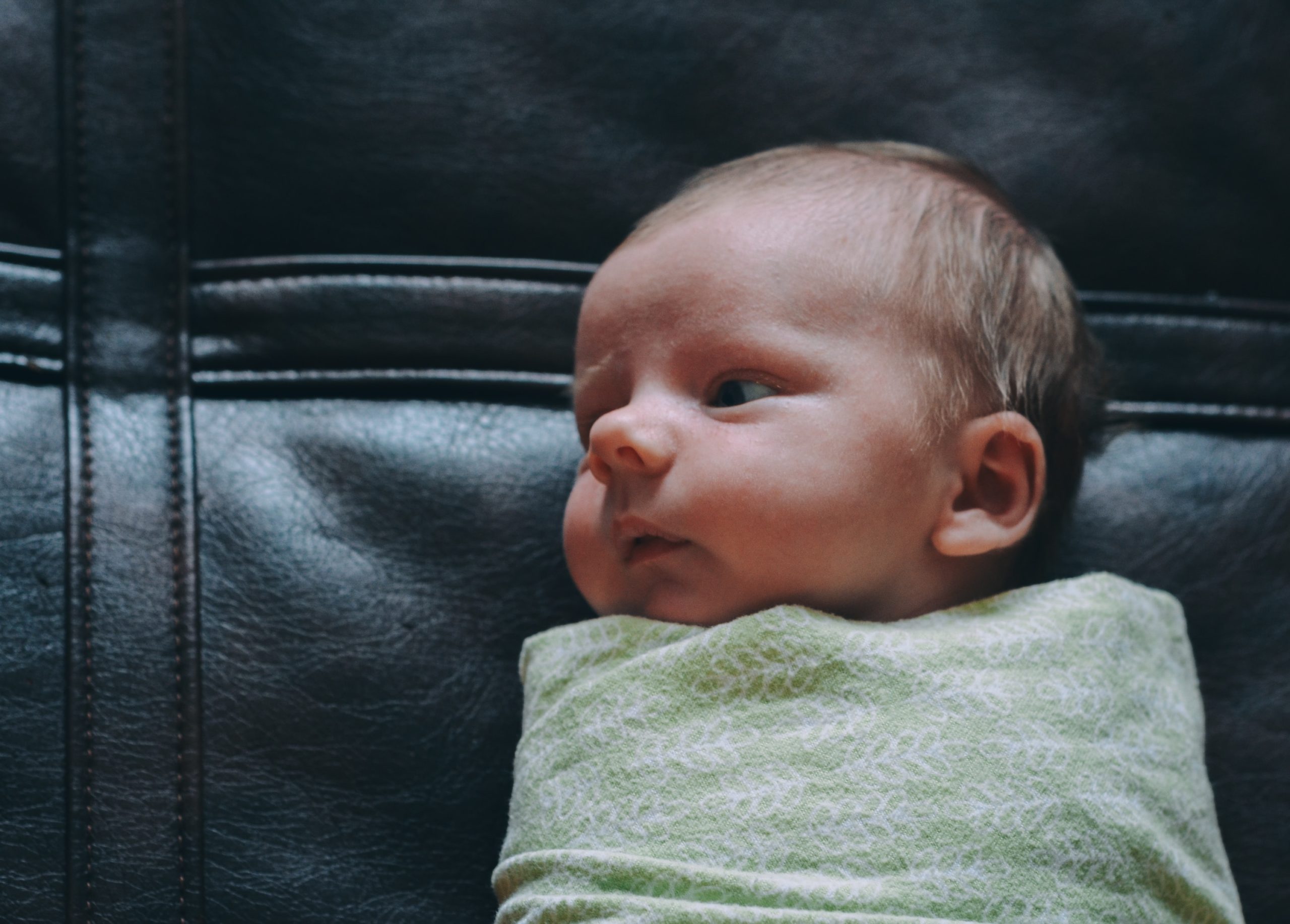 baby wrapped in a green swaddle.