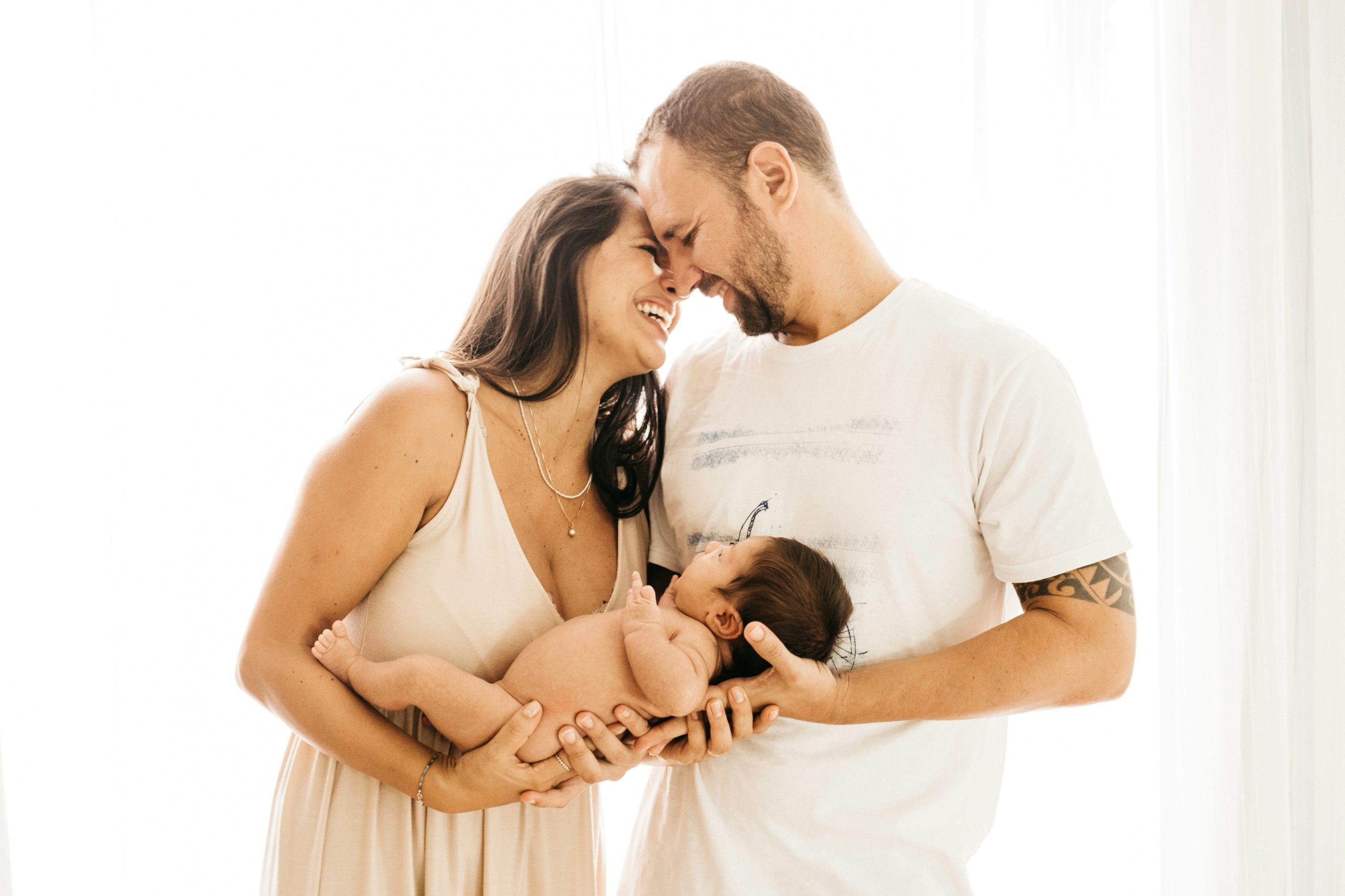 Couple nuzzling heads while holding their baby together.