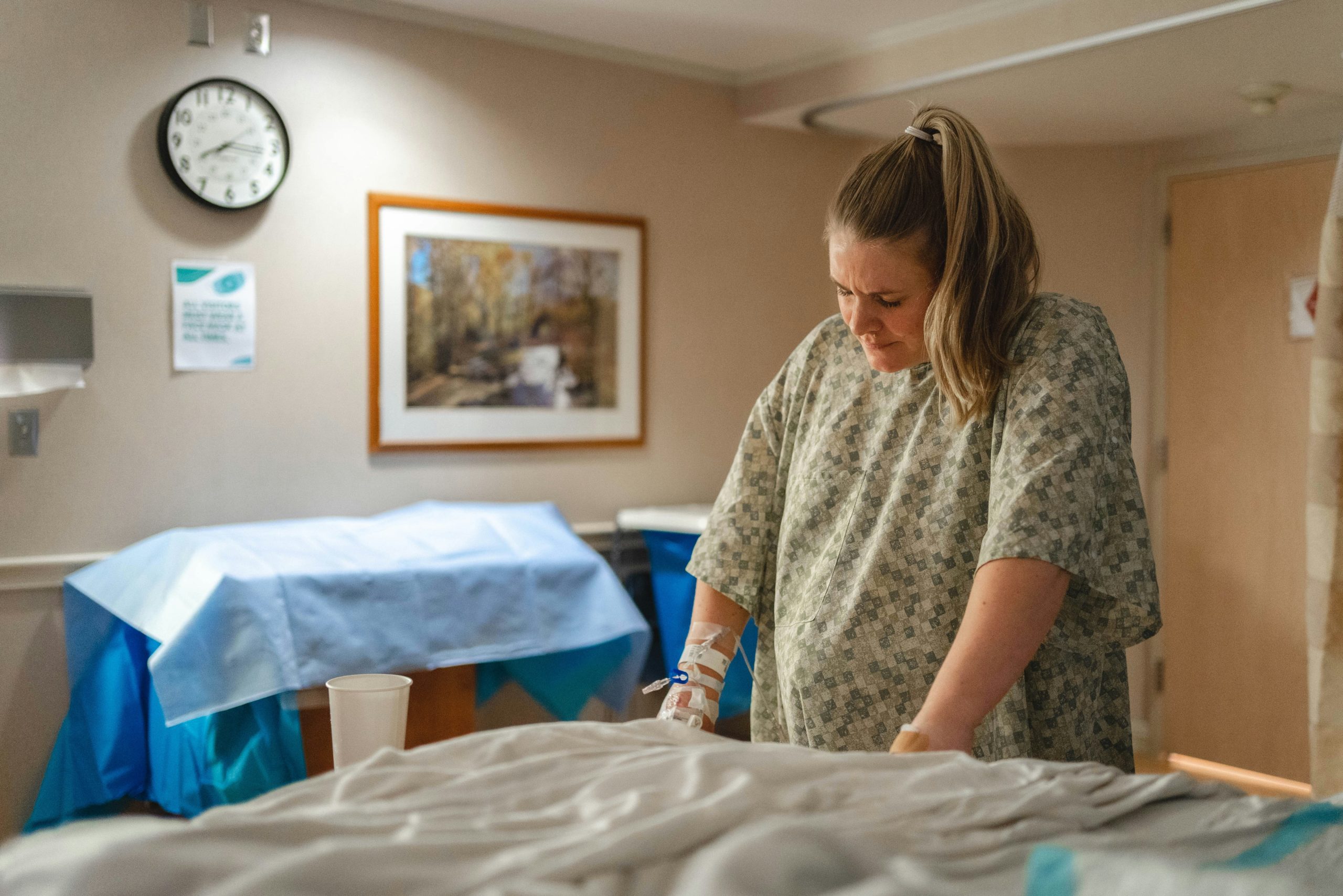 birthing person wearing a hospital gown and leaning on hospital bed while in labor.