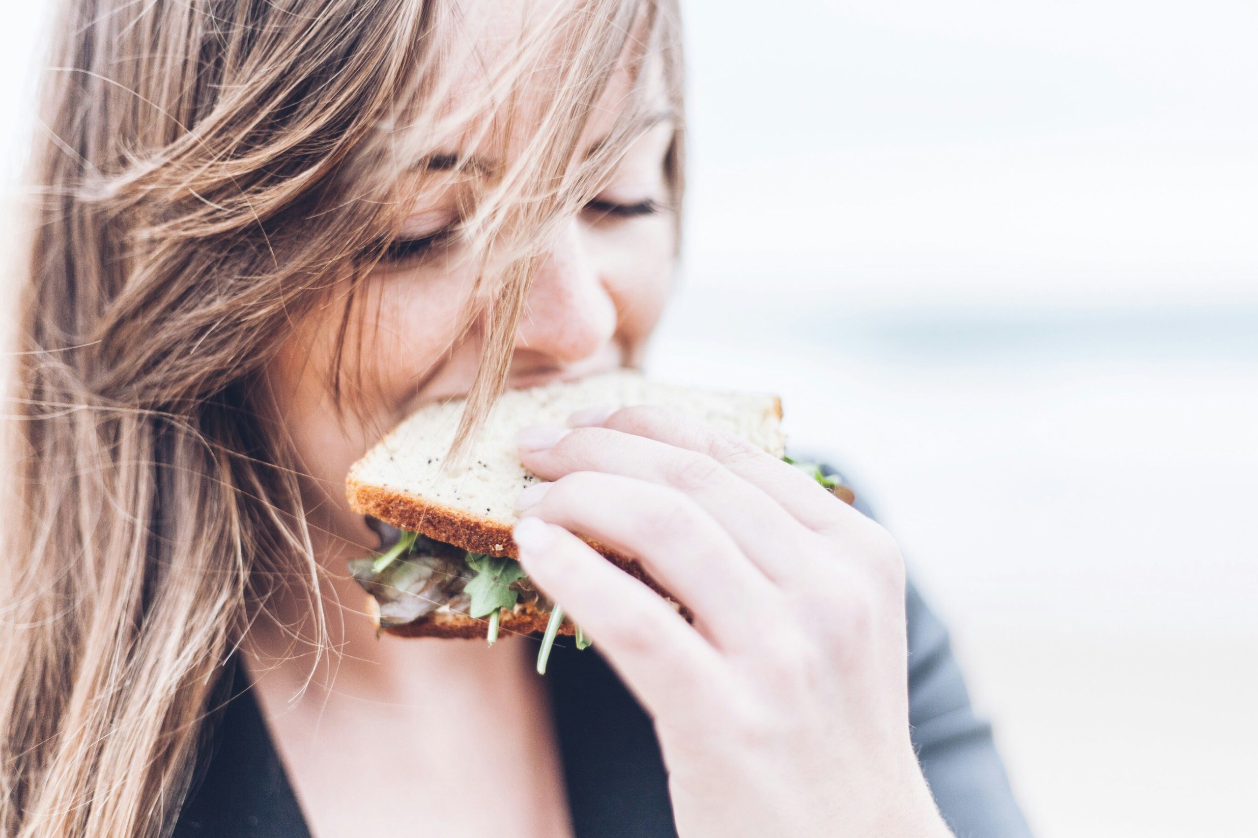 Person taking a bite from a sandwich.