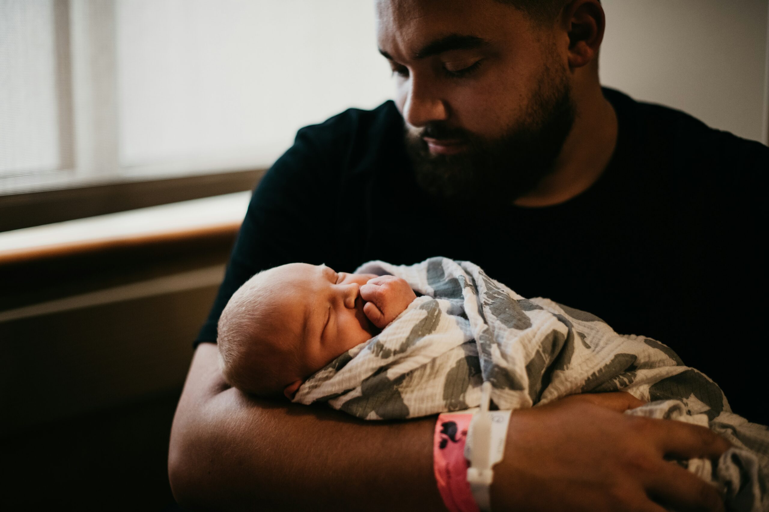 Partner holding a newborn, swaddled baby.