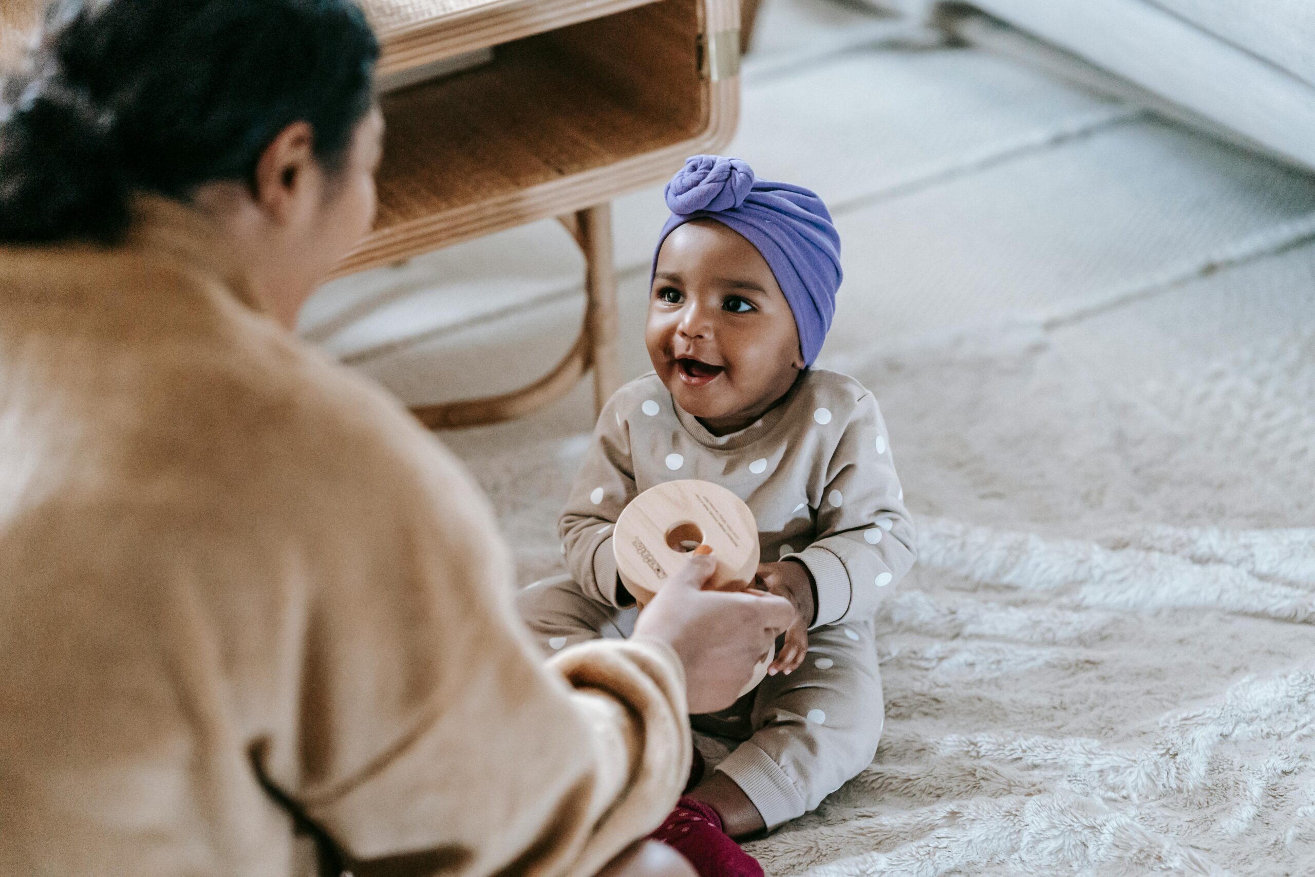 Parenting holding a toy out to their baby.