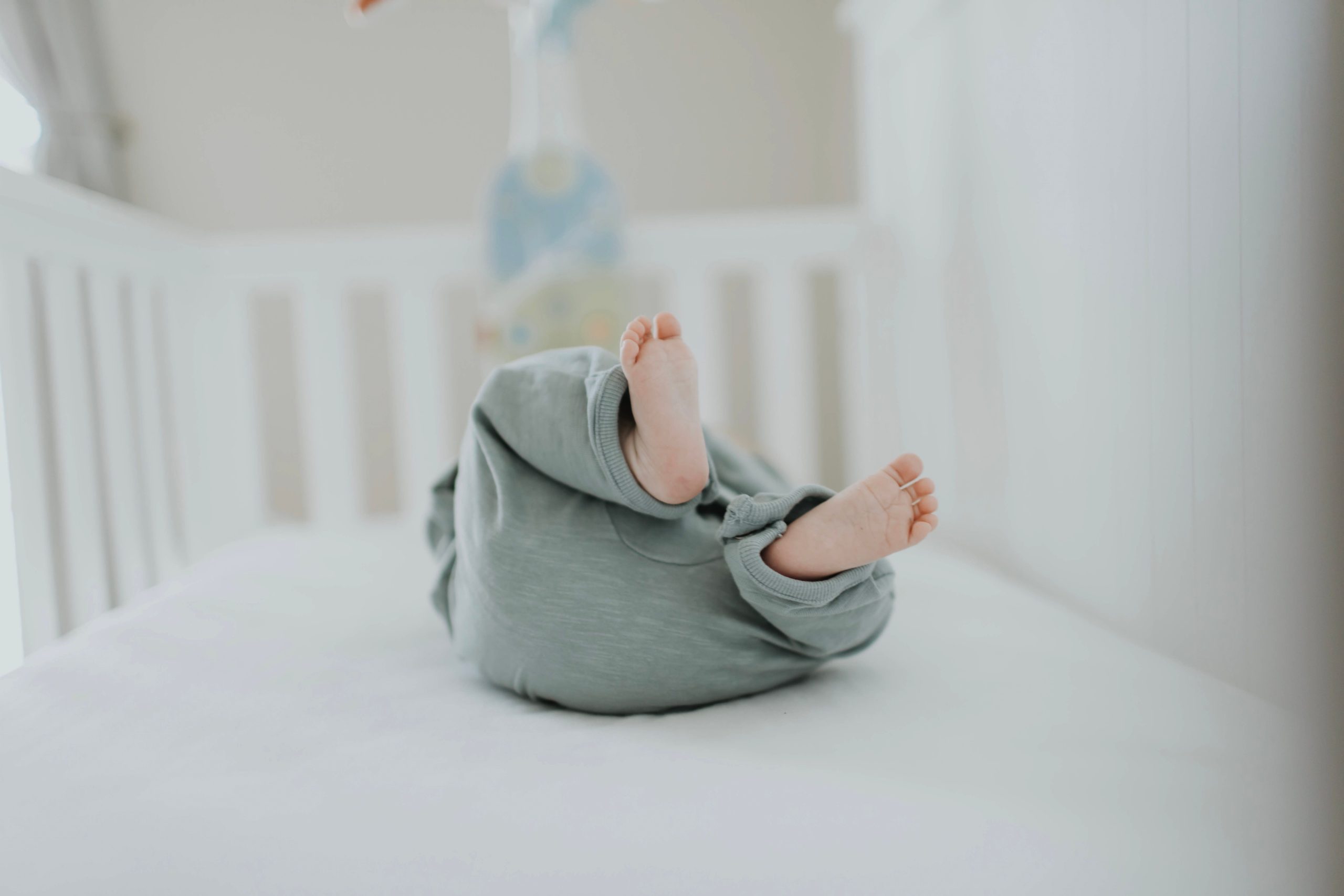 A baby in a crib wearing a green outfit.