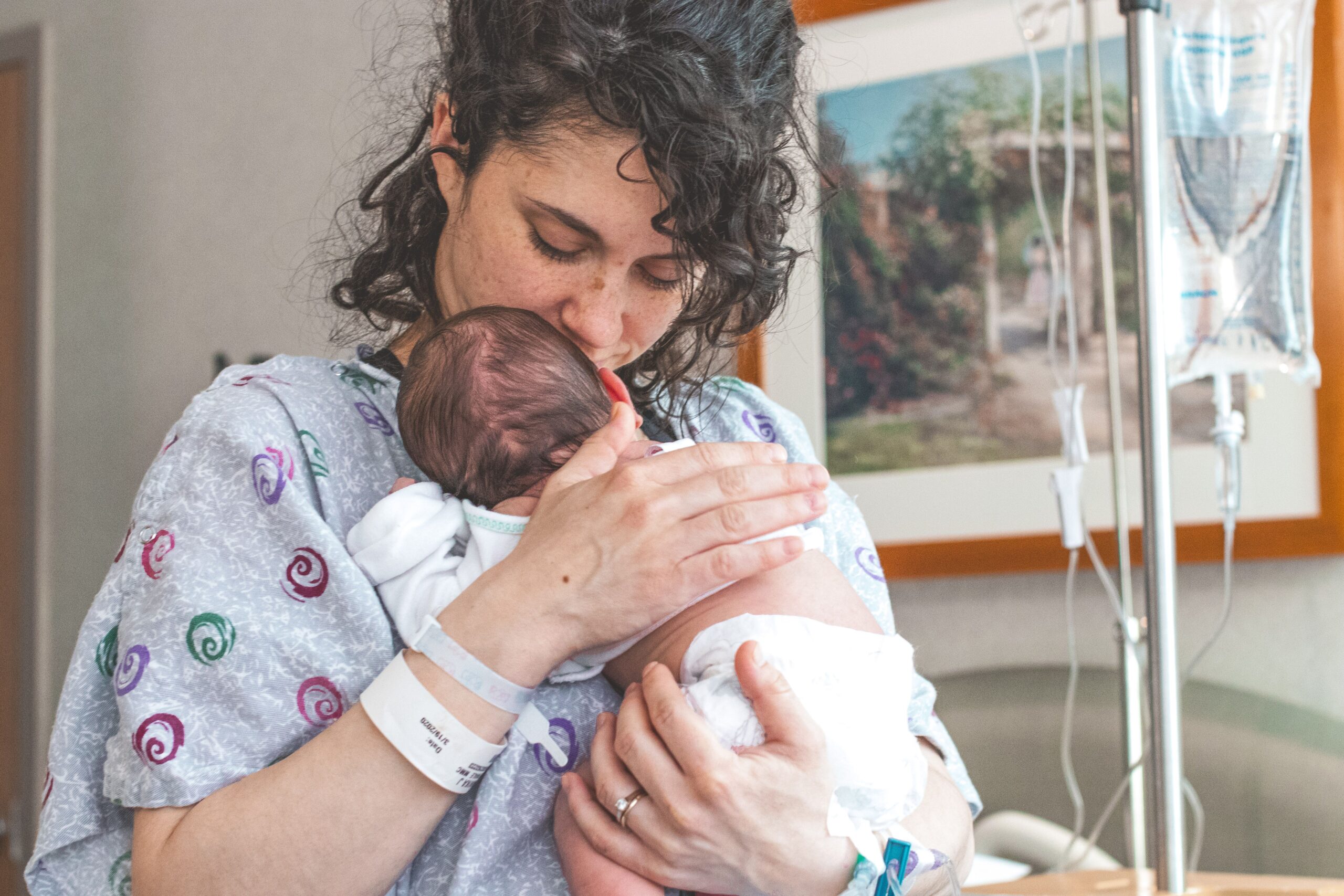 Parent holding their baby while wearing a hospital gown after cesarean birth.