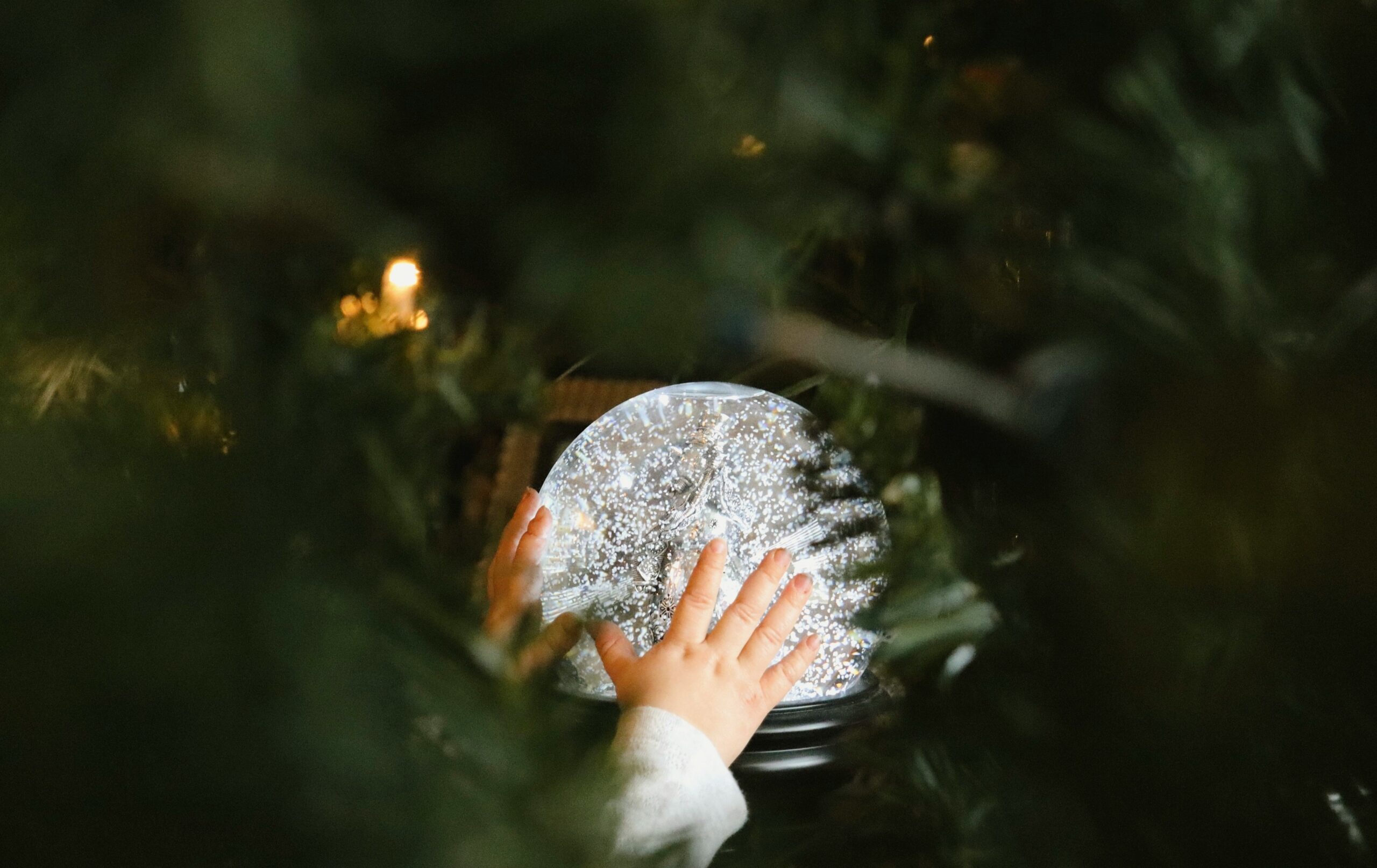 Child's hands reaching for a snow globe.