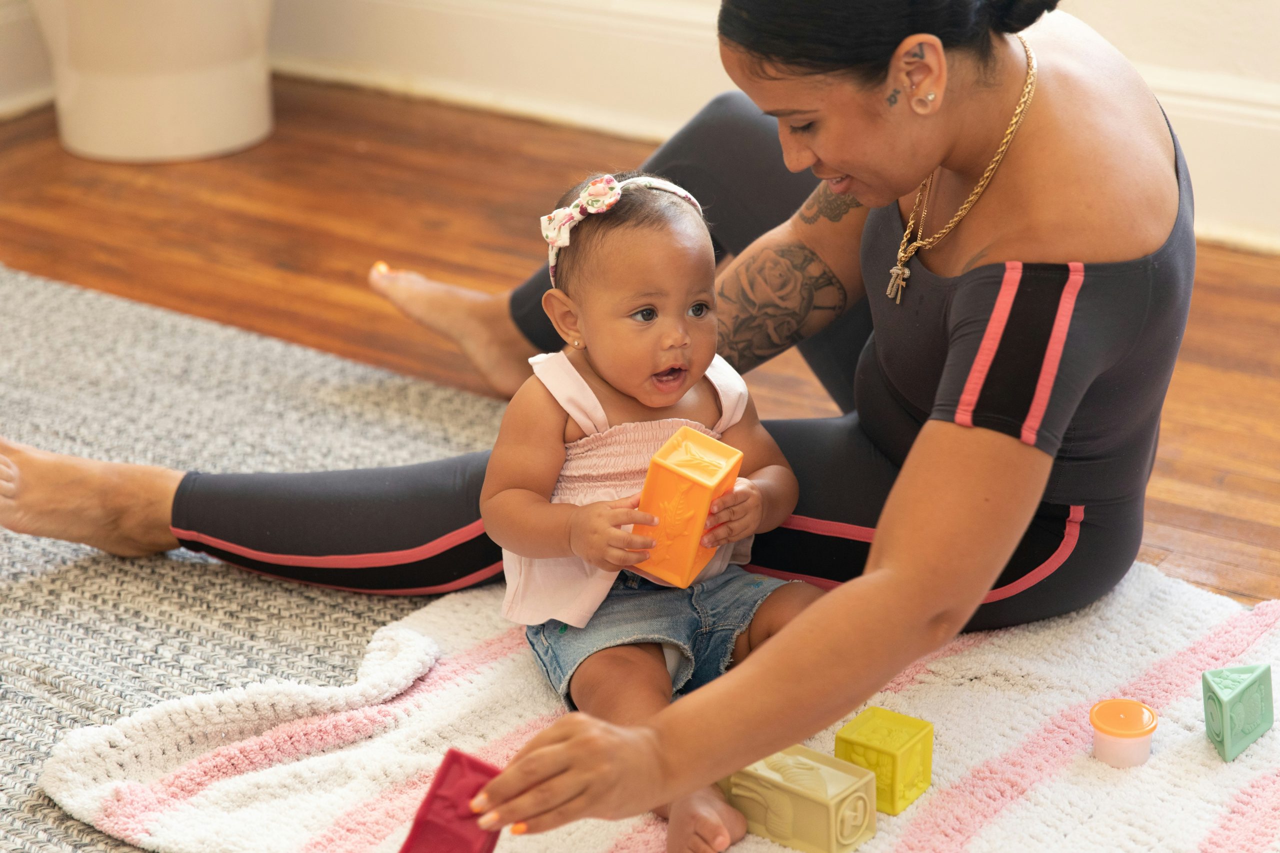 parent sitting on a blanket with their baby, exploring blocks together